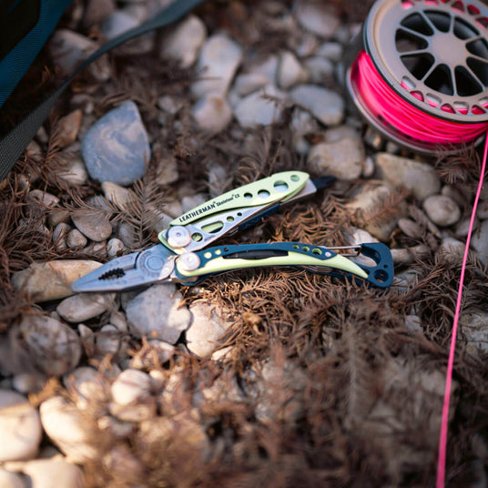 Translation missing: en.Verdant Skeletool® CX multi-tool on rocky surface with fishing line roll in background