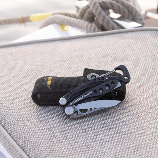 Translation missing: en.Black & stainless Leatherman Skeletool® CX with nylon sheath on a textured surface