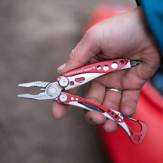 Translation missing: en.Hand holding a Red Leatherman Skeletool® RX multi-tool, showcasing its pliers and sleek red design
