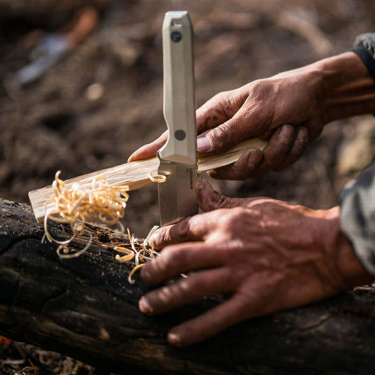 Translation missing: en.Person using an Alpine Leatherman Pioneer™ knife to carve wood shavings outdoors