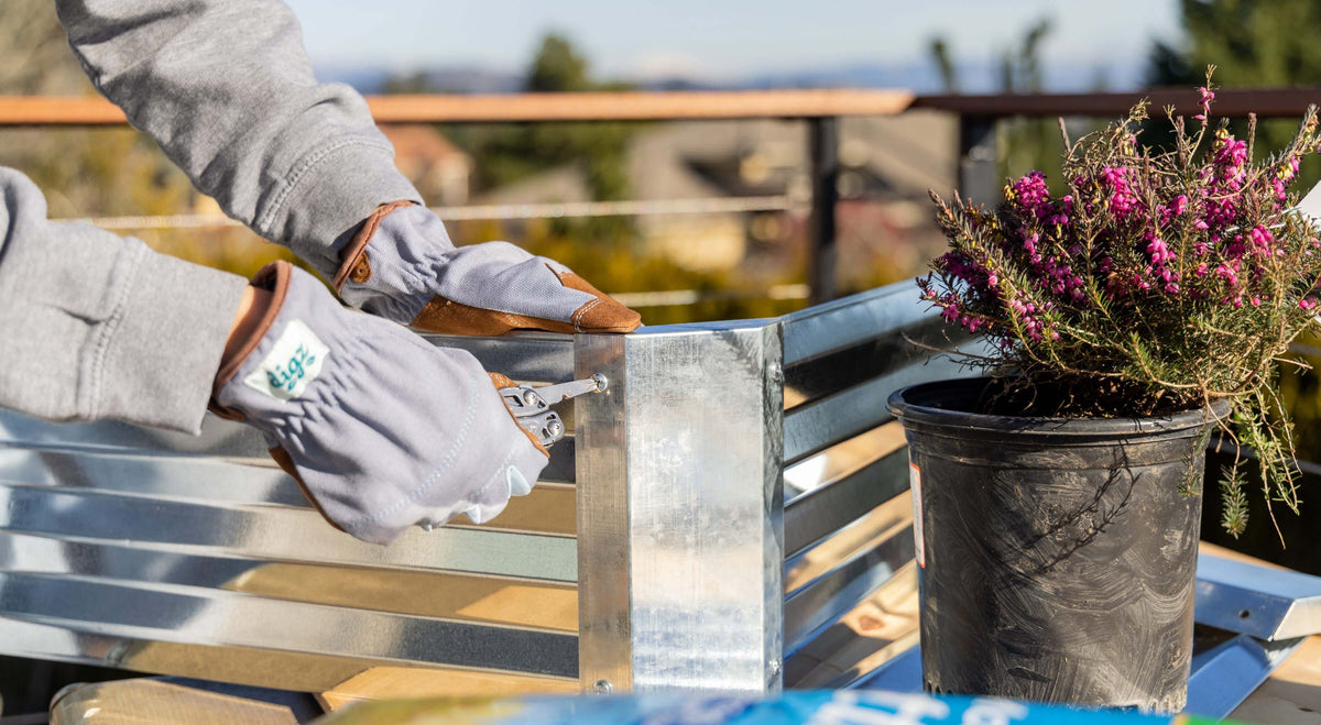 Person wearing gloves using a Stainless Steel Leatherman Wingman® to fasten a metal panel for gardening.