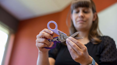 Translation missing: en.Melissa Lee holding the Orchid Leatherman Raptor® Rescue demonstrating it's versatility
