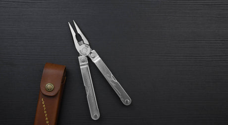 Translation missing: en.Stainless steel Leatherman PST® pliers on a dark background with a Leatherman brown Heritage sheath