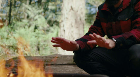 Translation missing: en.Man warming hands by a campfire in the forest