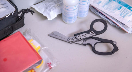 Translation missing: en.Black Leatherman Raptor® Rescue scissors on a table next to first aid supplies