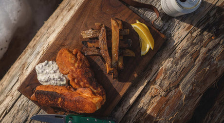 Translation missing: en.Delicious meal of fish, fries, and sauce on wooden platter