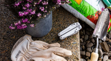 Translation missing: en.Stainless Steel Leatherman Surge® multi-tool beside gardening gloves and potting soil, perfect for outdoor projects