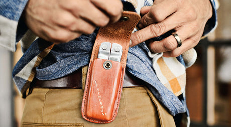 Translation missing: en.Person showcasing a brown Leatherman Heritage sheath on the side of a belt with a tool inside