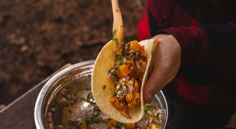 Translation missing: en.Cholula camp taco with delicious filling and fresh toppings being held over a bowl