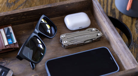 Translation missing: en.Leatherman Wingman on table with other everyday carry items ike sunglasses and ear pods