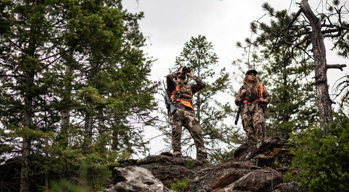 Hunters in the wilderness looking for game and carrying hunting gear.