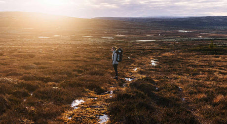 Translation missing: en.A woman is standing in a field as the sun rises over the horizon 