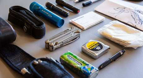 Translation missing: en.Stainless Steel Leatherman Charge® multi-tool with other everyday items on a table