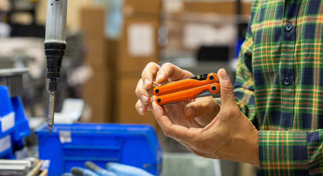 Translation missing: en.Jackson Wang holding an orange Leatherman Wave® Alpha multitool in a workshop setting