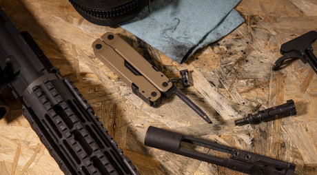 Translation missing: en.Coyote Tan Super Tool® 300M on a workbench with firearms and cleaning supplies