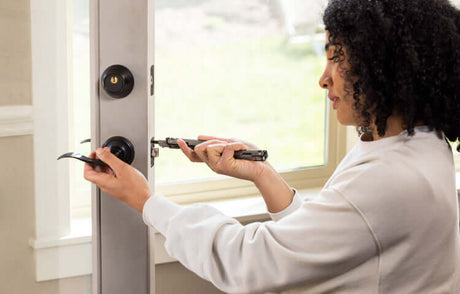 Translation missing: en.Woman using a Black DLC &amp; Stainless Steel Leatherman ARC® to install a door lock with precision and ease