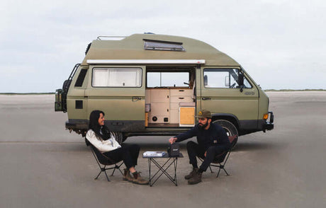 Translation missing: en.Couple enjoying adventure by their green van on a beach