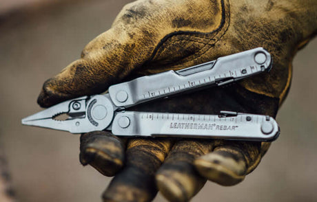 Translation missing: en.Stainless Steel Leatherman Rebar® multi-tool held in a dirty gloved hand