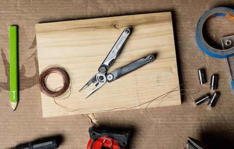 Translation missing: en.Stainless Steel Leatherman Wave® Plus on a wooden surface with art supplies