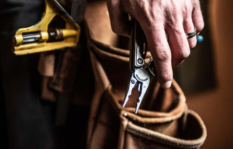 Translation missing: en.A craftsman holds the Stainless Steel Leatherman Charge®+ TTi multitool, ready for heavy-duty tasks