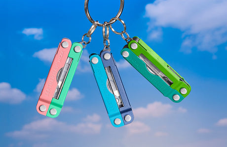 Translation missing: en.A Teal Twist, Lavender Mist and Bayside Micra multitool hanging from a keychain ring in front of a sky backdrop