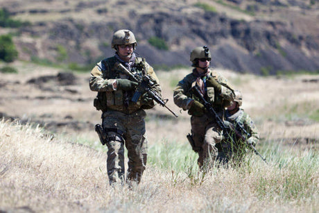 Translation missing: en.Military personnel on a mission carrying weapons in a natural outdoor setting