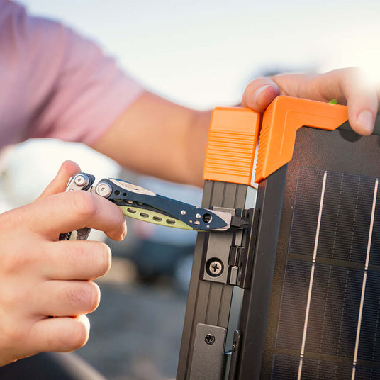 Translation missing: en.A person using a Verdant Skeletool® CX multitool to adjust a solar panel outdoors in sunlight