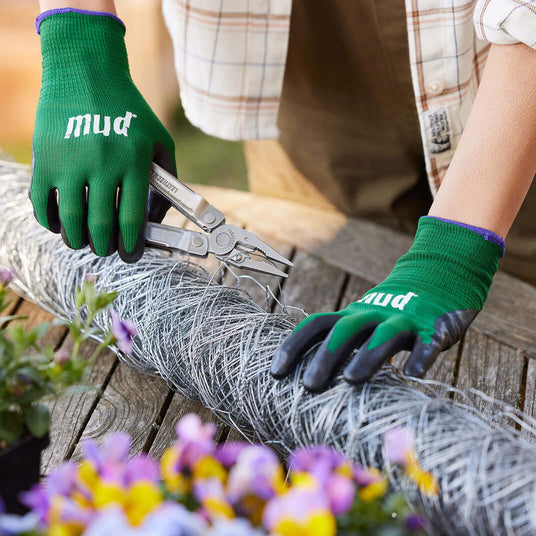 Translation missing: en.Person using a Stainless Steel Leatherman Rebar® pliers while gardening with a mesh wire frame and flowers
