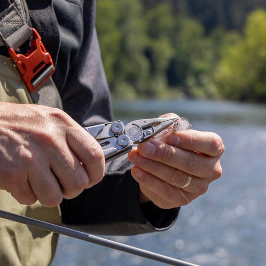 Translation missing: en.Person using a Stainless Steel Leatherman Wave® Plus multitool for fishing on the river