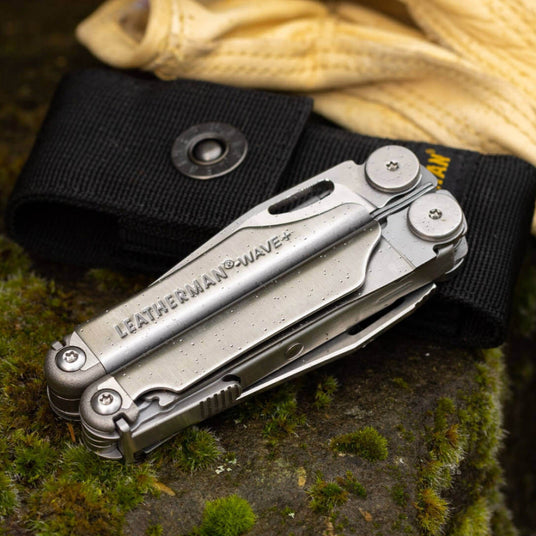 Translation missing: en.Leatherman Wave® Plus multi-tool with black nylon sheath on a mossy surface, showcasing its versatility and durability