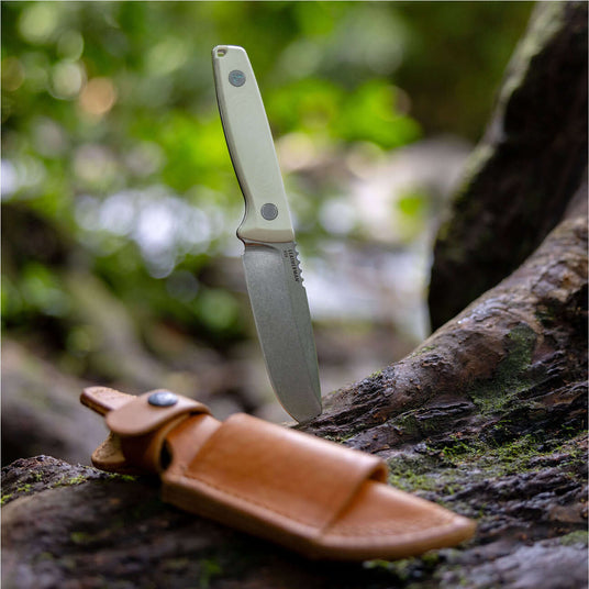 Translation missing: en.Alpine Leatherman Trac™ knife on a log beside a leather sheath, showcasing outdoor gear and craftsmanship