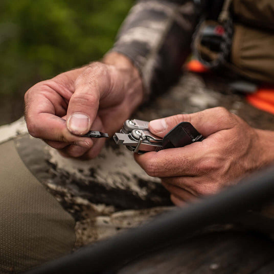 Translation missing: en.Person putting a bit on a Stainless Steel Leatherman Wave® Plus multitool in a natural setting