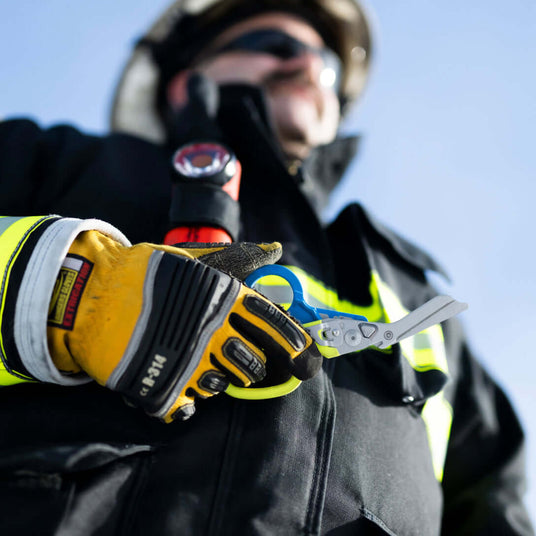 Translation missing: en.Firefighter holding a Yellow/Blue Leatherman Raptor® Rescue in a rescue-ready stance