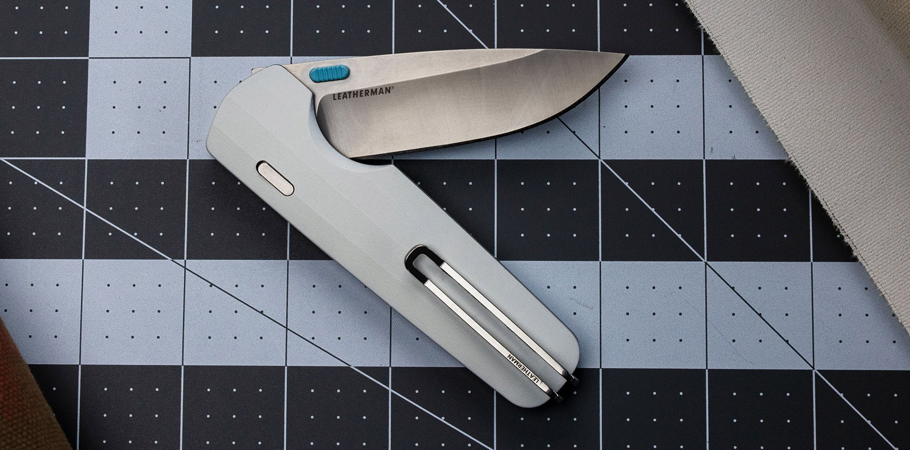 Alpine Leatherman Blazer™ knife displayed on a grid cutting mat, showcasing its sleek design and open blade.