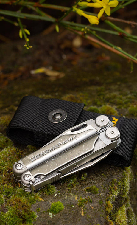 Translation missing: en.Stainless Steel Leatherman Wave® Plus multi-tool on a black sheath, set against a natural mossy stone background