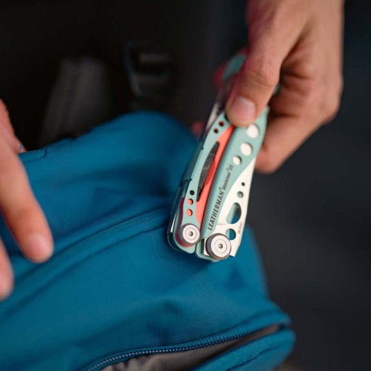 Translation missing: en.Person retrieving a Paradise Skeletool® CX multi-tool from a blue backpack, showcasing its compact design and functionality