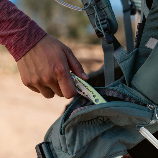 Translation missing: en.Hand reaching into backpack pocket to retrieve a Verdant Leatherman Skeletool® KB for outdoor activities