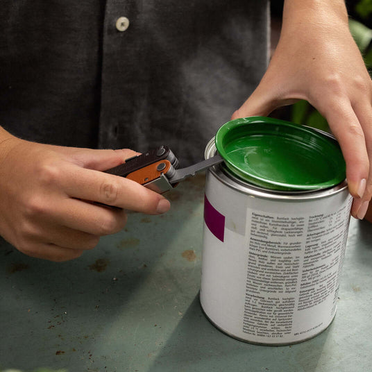 Translation missing: en.Person using a Burnt Sienna Leatherman Rebar® to open a paint can with a green lid