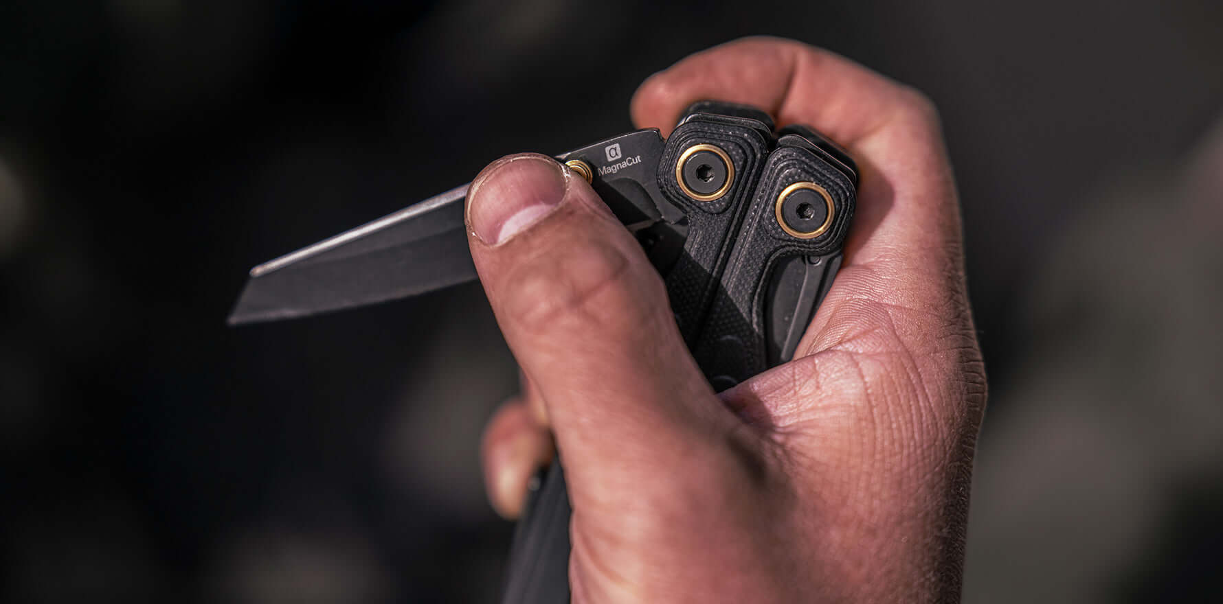 Close-up of a hand using the thumb stud to open the MagnaCut knife blade with one hand on the Leatherman Wave® Alpha Obsidian.
