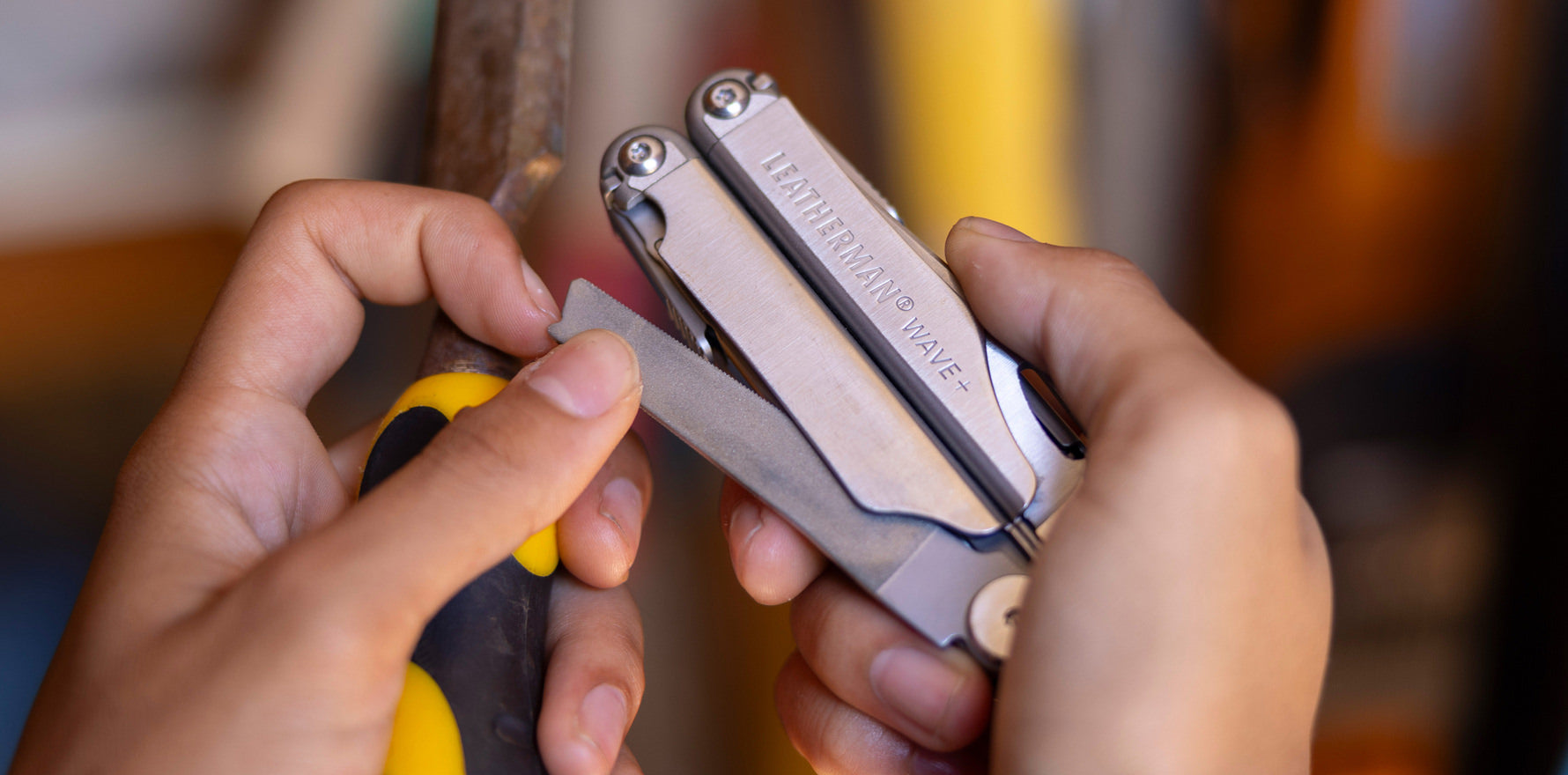 Hands ejecting the file on a stainless steel Leatherman Wave® Plus multitool.