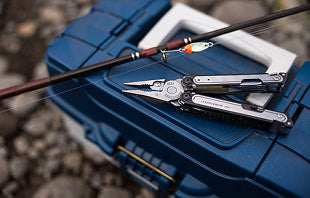 Translation missing: en.A fishing rod, Leatherman Arc, and a fishing pole are resting on the ground, showcasing their equipment for a day of fishing