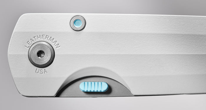 Translation missing: en.Close-up image of a Leatherman folding knife handle in Alpine white, showcasing precision hardware details, engraved “LEATHERMAN USA” branding, and a textured blue locking mechanism for enhanced control and usability