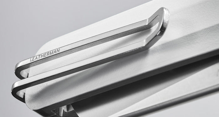 Translation missing: en.Close-up image of a Leatherman knife's sleek metal pocket clip, engraved with the Leatherman brand name, attached to a minimalist white handle against a soft gray background