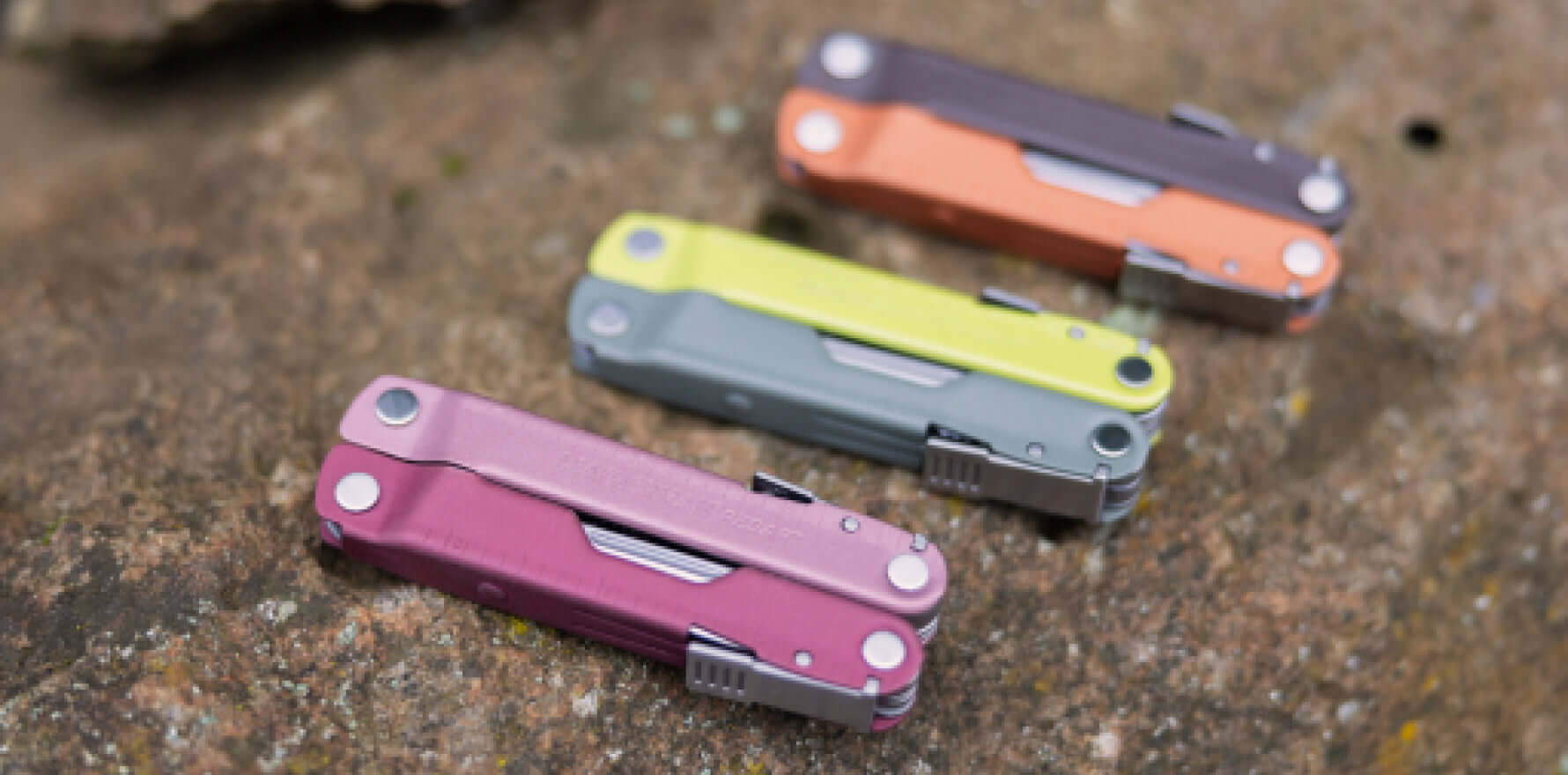 Leatherman Rebar® multi-tools in vibrant colors on a natural stone surface.