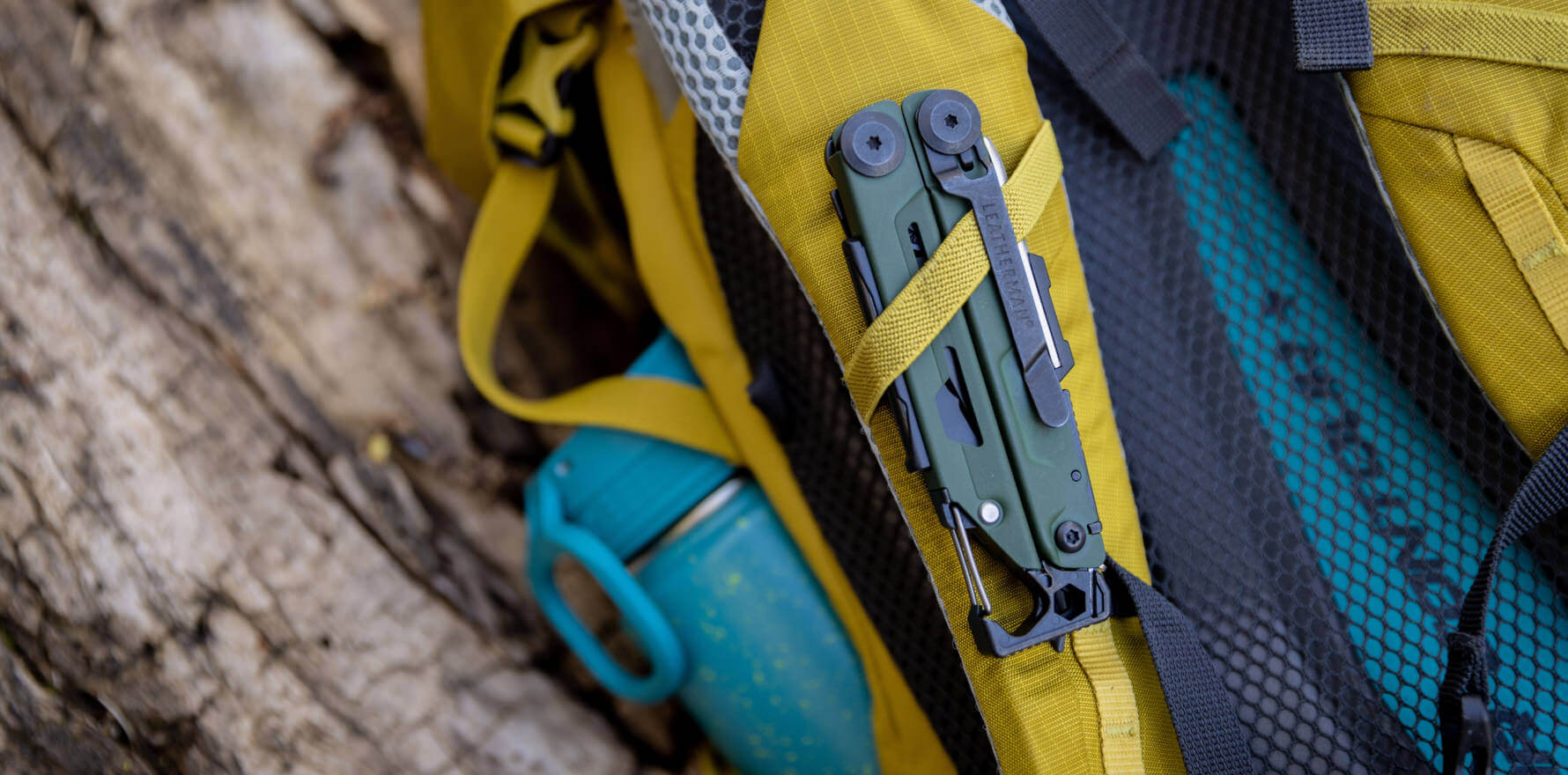 Green Leatherman Signal® multi-tool secured to a yellow backpack, ideal for outdoor adventures.
