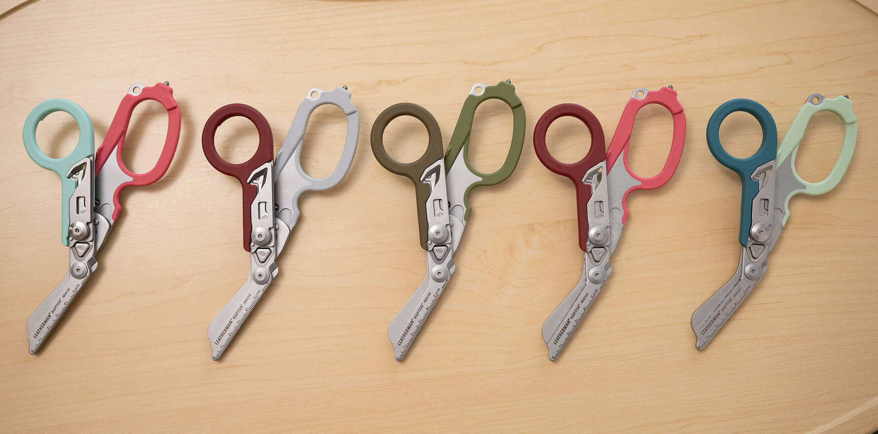 Five pairs of colorful Leatherman Raptor® Rescue shears displayed on a table, highlighting their unique design and colors.
