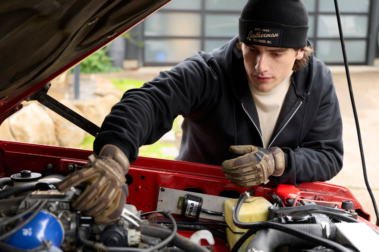 Translation missing: en.A person wearing a black Leatherman Vintage Beanie working under the hood of a red vehicle